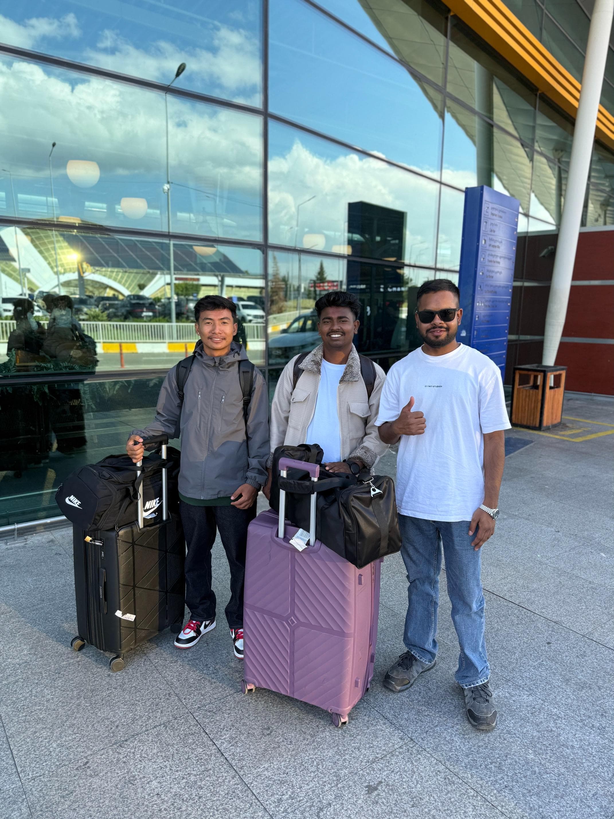 Three newly arrived students with their suitcases outside Tbilisi airport
